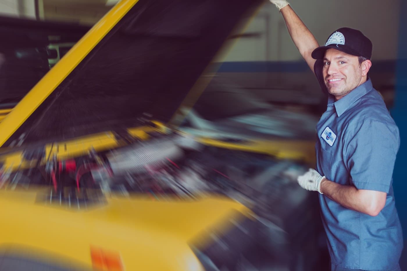 A mechanic under a hood while the bay moves past