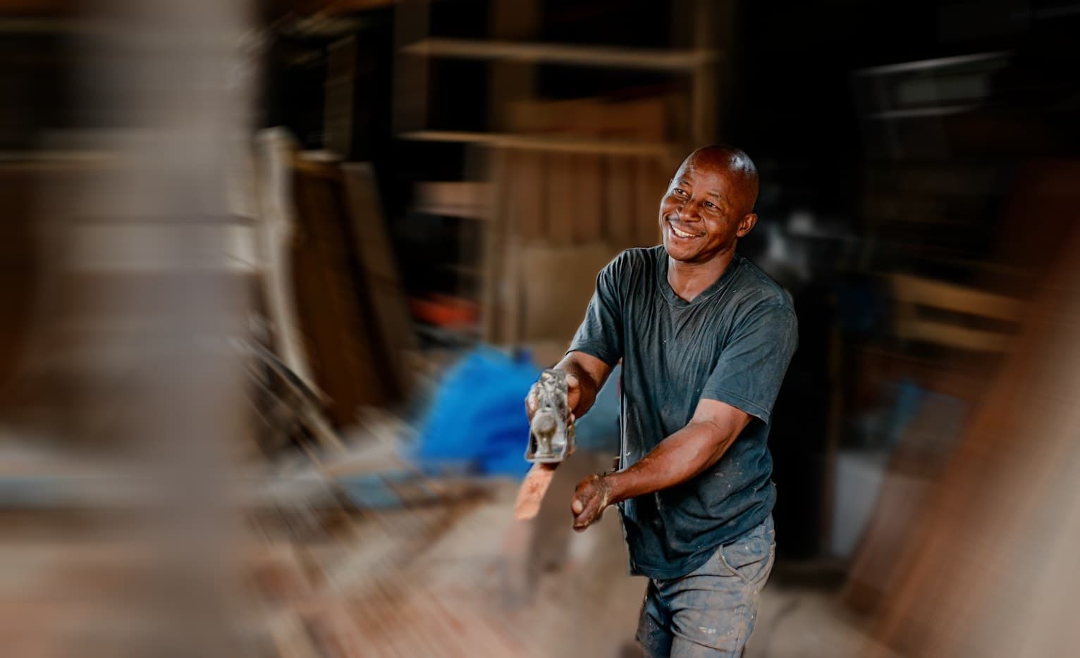 A contractor works at a workbench while the shop moves around him